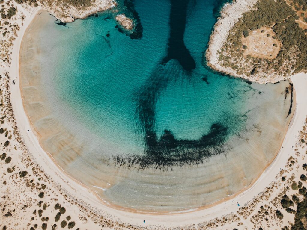 Stunning aerial view of a horseshoe-shaped bay with turquoise waters and sandy beach.